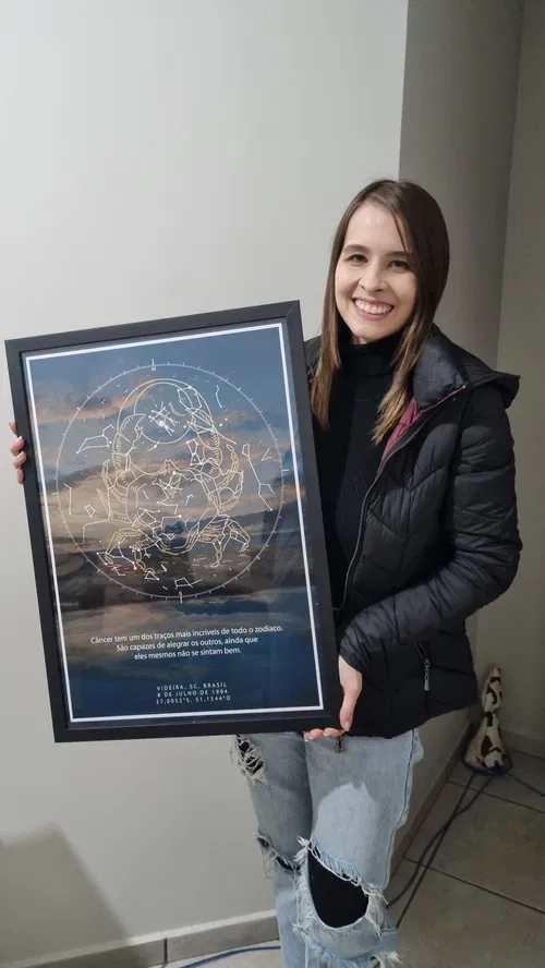 Menina segurando grande mapa estelar do seu nascimento com tema do signo do zodíaco câncer