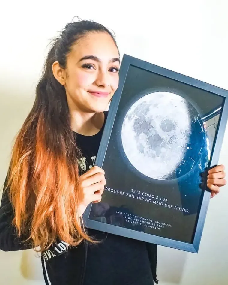 Aniversariante segurando um quadro com a lua do seu céu